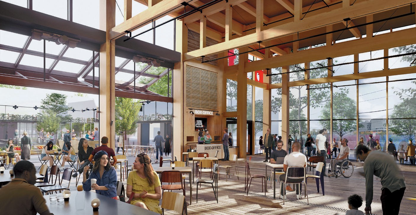 Atrium with timber beams, glass walls, café seating, box office, and people gathered in bright daylight.