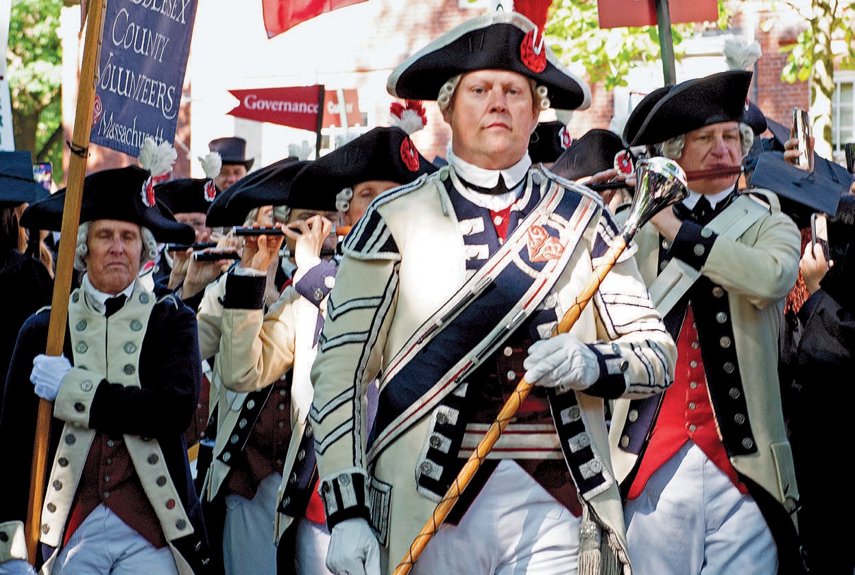 Colonial-era fife and drum corps marches in historical uniforms during commencement procession.