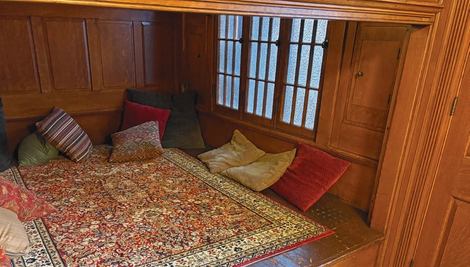 Wood-paneled platform bed alcove with patterned rug and decorative pillows.
