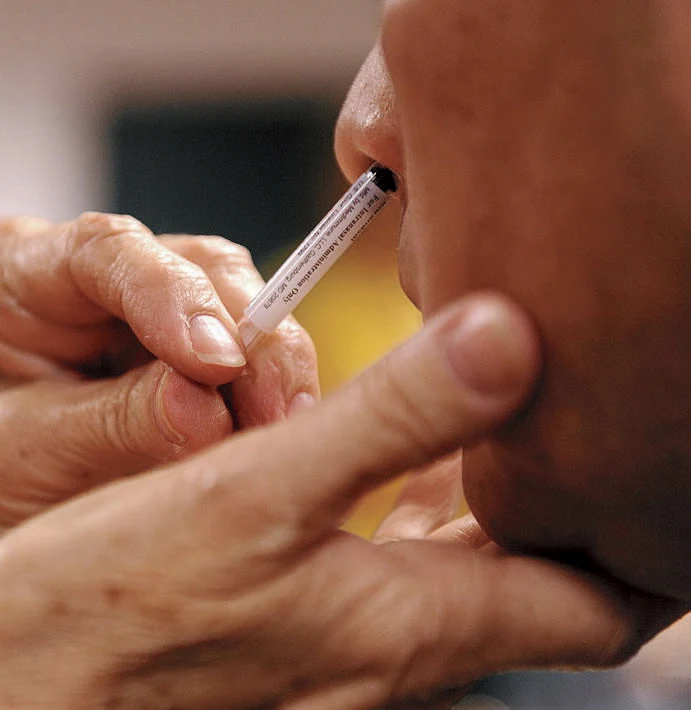 Person getting a vaccine delivered through their nostril