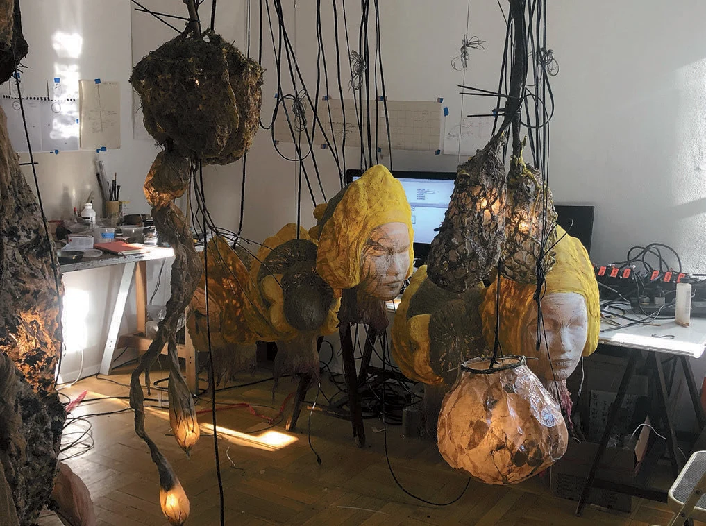 paper mache objects hanging in a small room, some shaped like heads