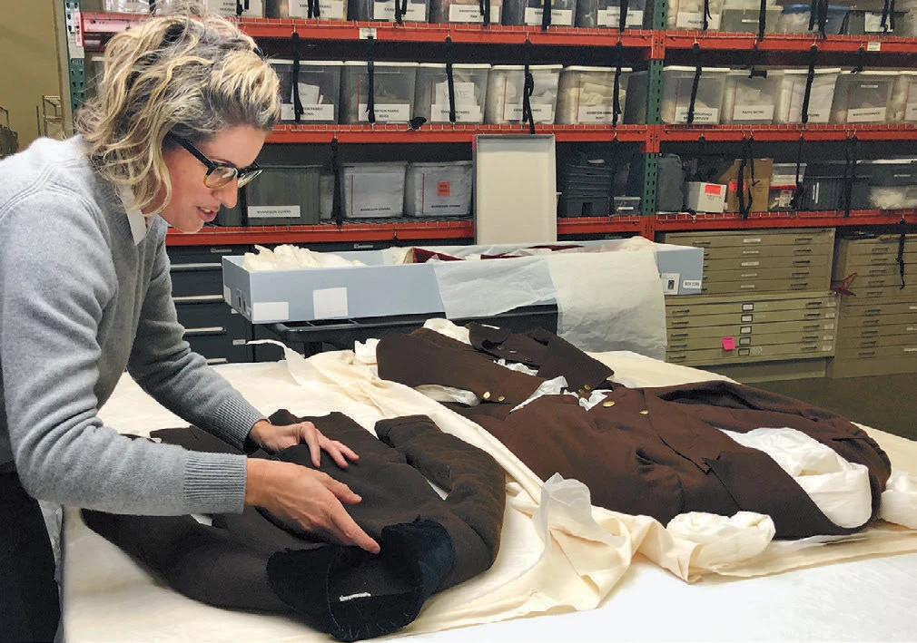 A woman looking at a table with three suit jackets