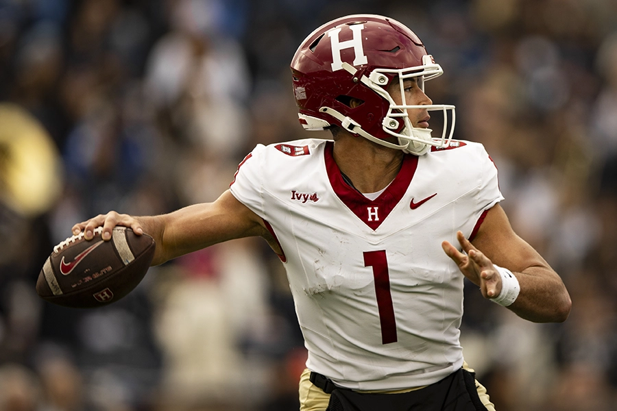 Quarterback in a Harvard uniform prepares to throw a football during a game.