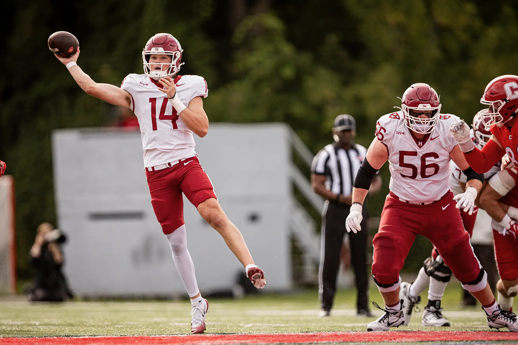 Harvard football player in white jersey gets ready to throw the ball