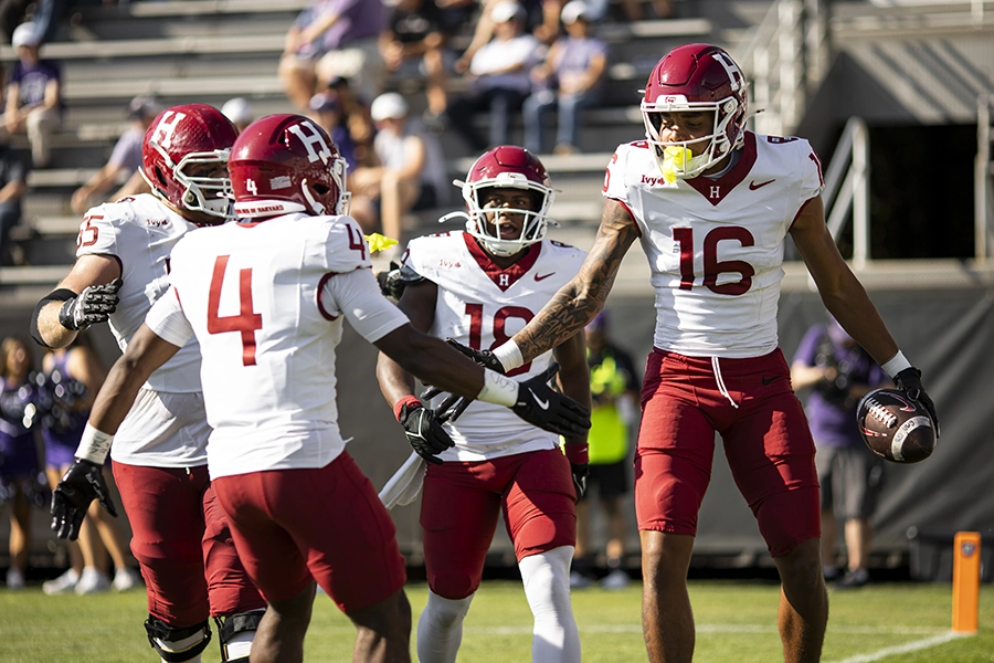 Harvard football players celebrate a touchdown as player number 16 holds the ball.