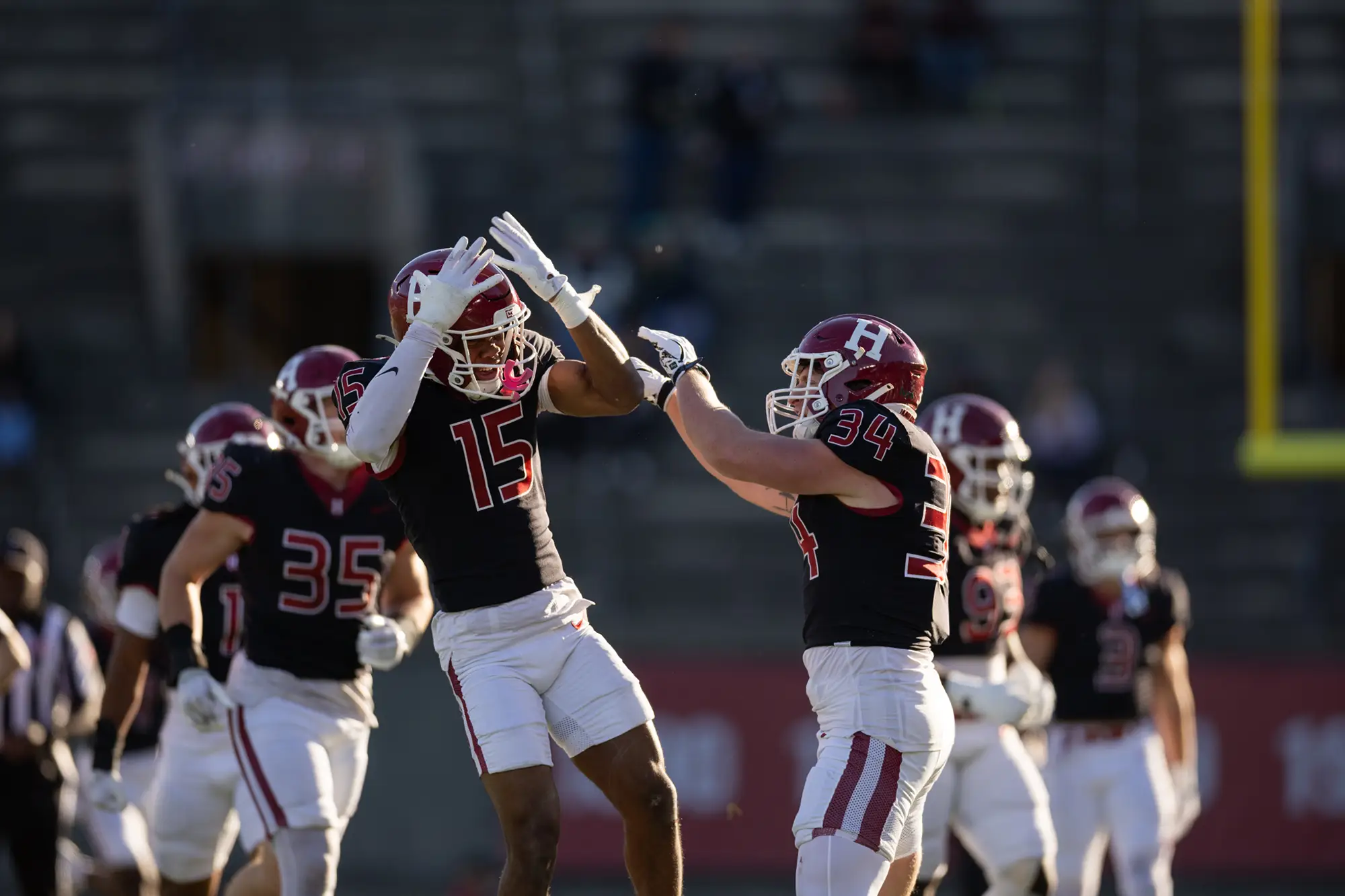 Harvard players #15 and #34, both wearing black uniforms, celebrate