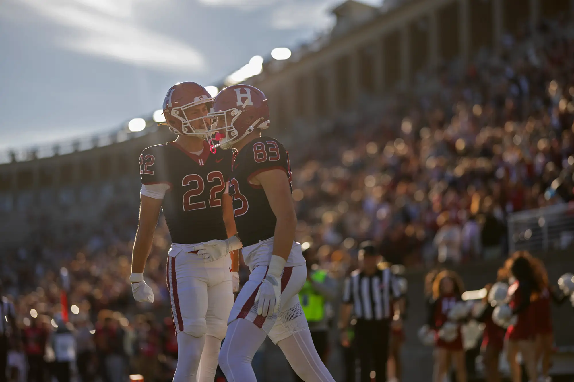 Harvard players #22 and #83, wearing a black uniform, celebrate 