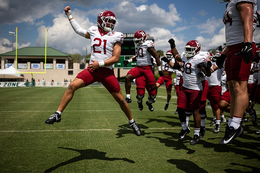 Harvard football players jump in unison during a pregame warmup or celebration.