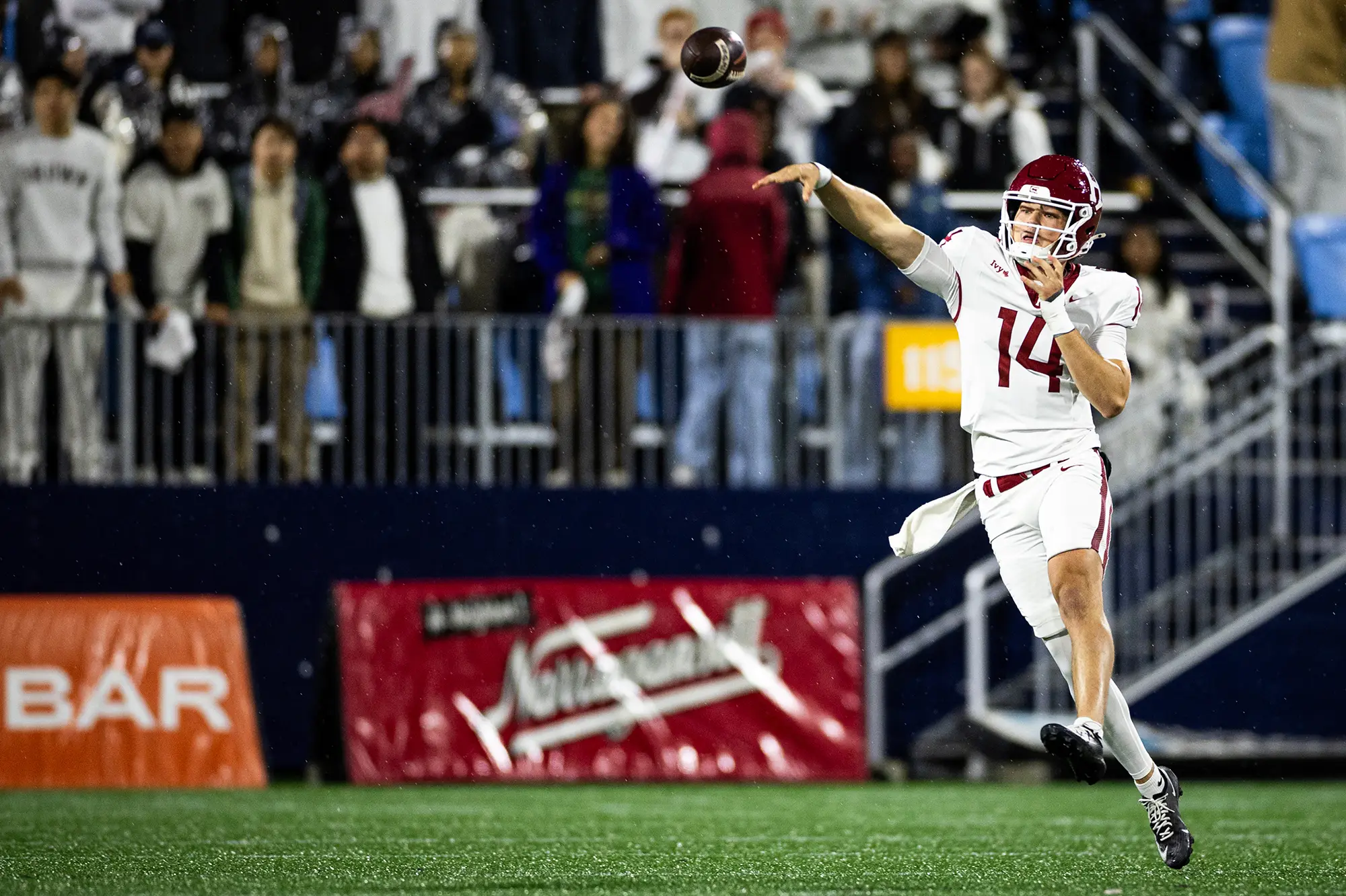 Harvard player #14, wearing a white uniform, throws the football