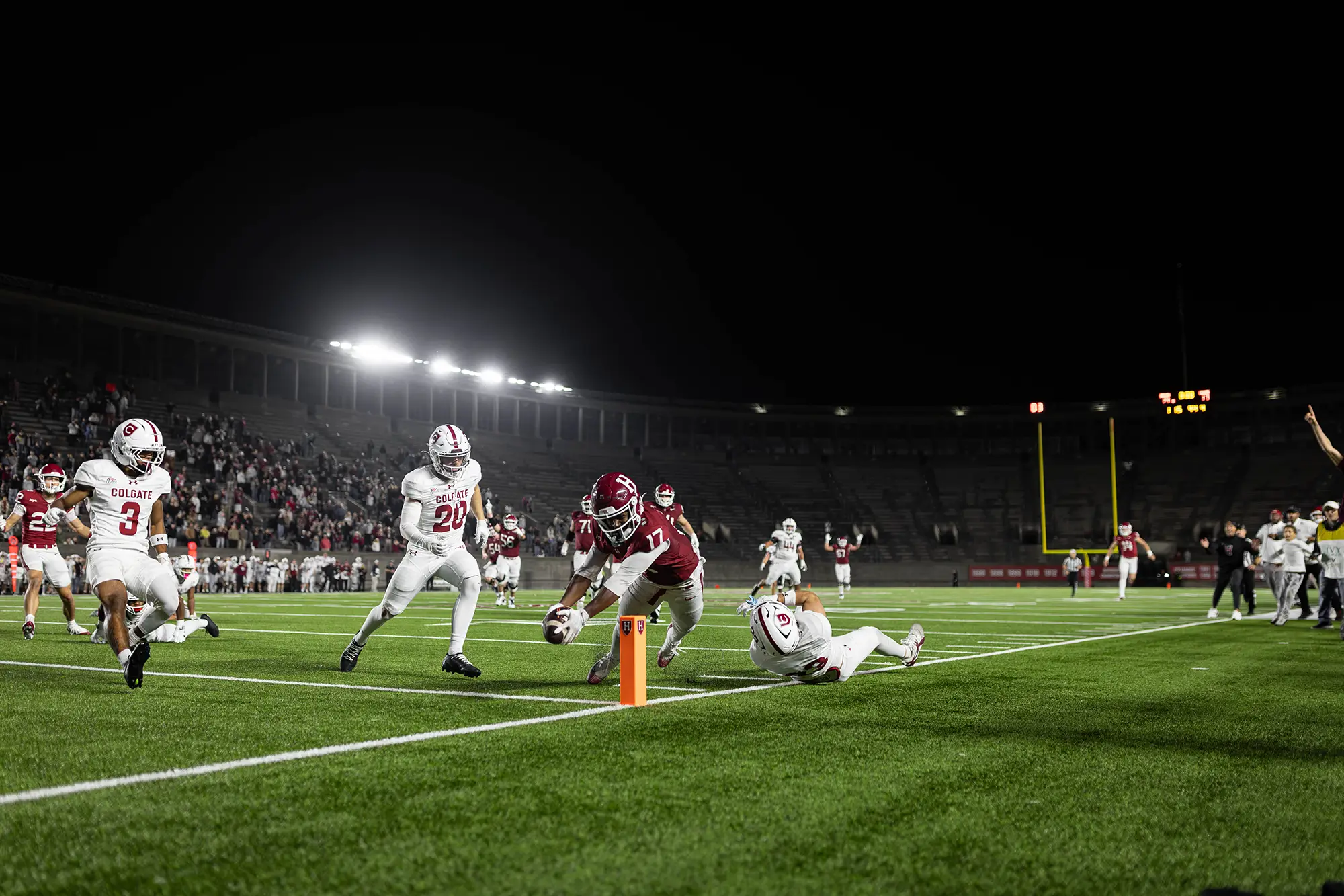 Harvard player #17 in a red unifrom grabs the ball with Colgate players in pursuit