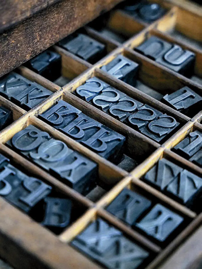 Wooden printer tray containing uppercase movable type blocks in various fonts.