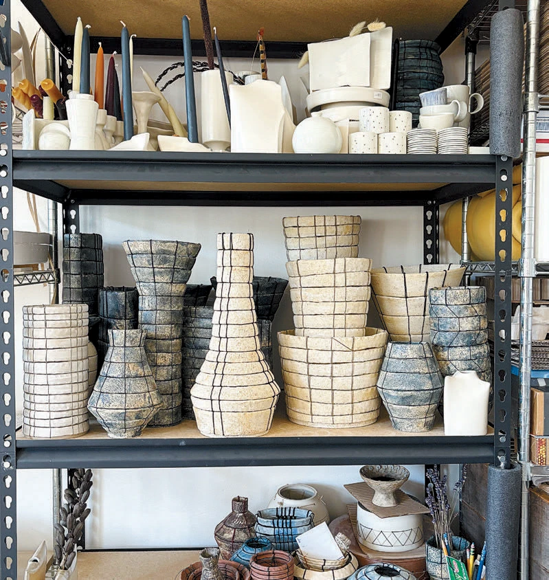 Shelves filled with handmade grid-textured ceramic vases and pottery.