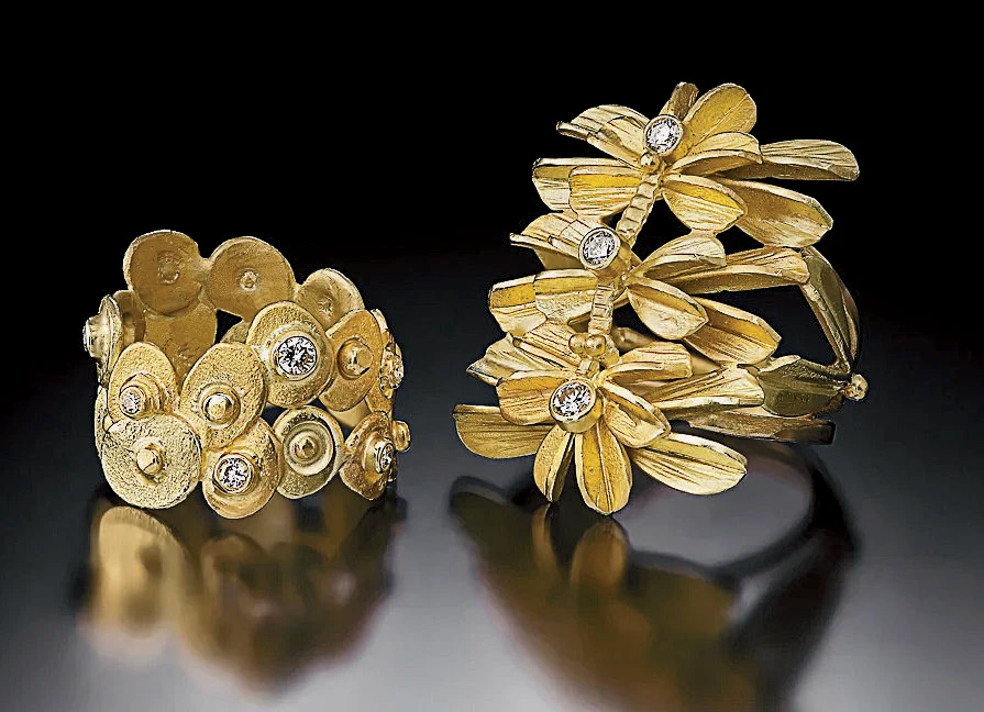 Two gold rings, one with discs and diamonds, the other with floral shapes and diamonds.