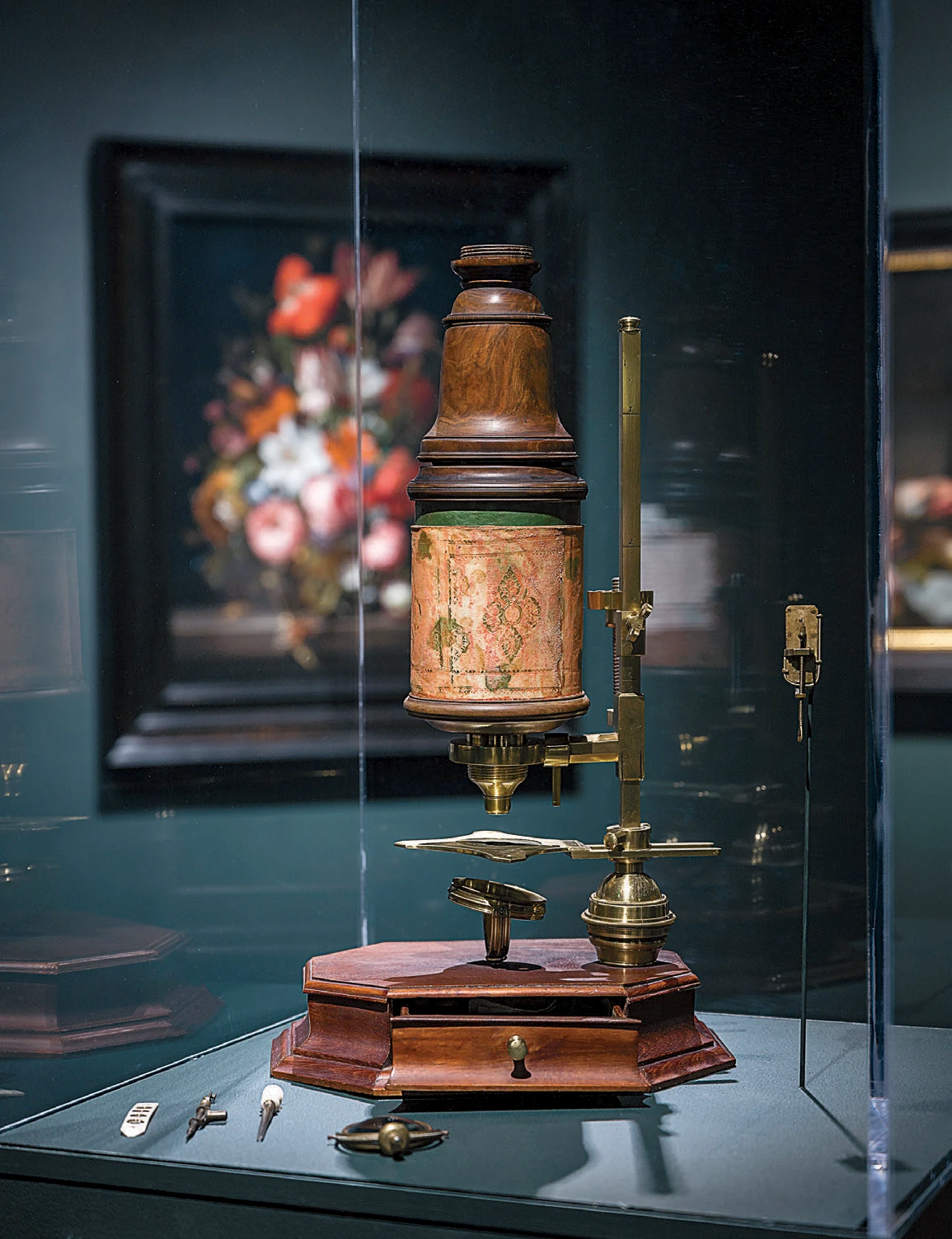Ornate antique microscope with brass and wood detailing displayed in a museum case.
