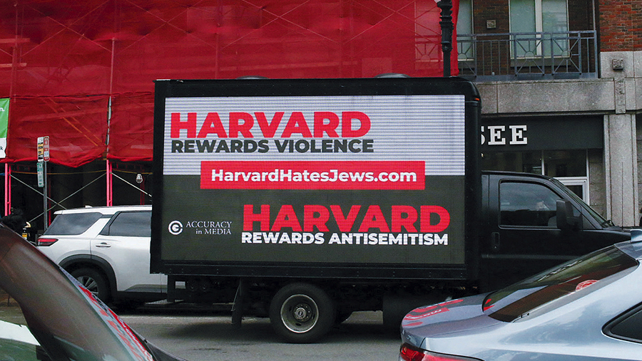 Truck with digital billboard reading “Harvard Rewards Violence” and “Harvard Rewards Antisemitism.”