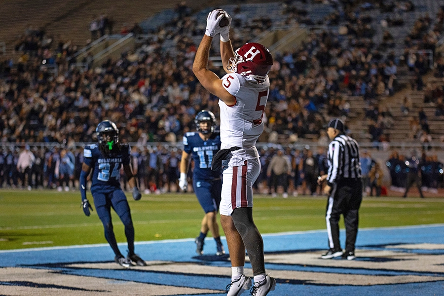 Harvard player catches football in the end zone as Columbia defenders and a referee look on.