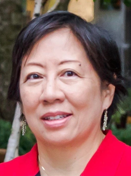 woman with short dark hair in red jacket, outdoors, slight smile