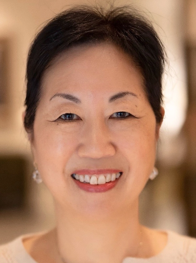 Short-haired woman smiling warmly, soft indoor background blur