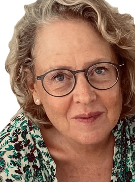 woman with glasses and curly gray hair, patterned top, gentle smile