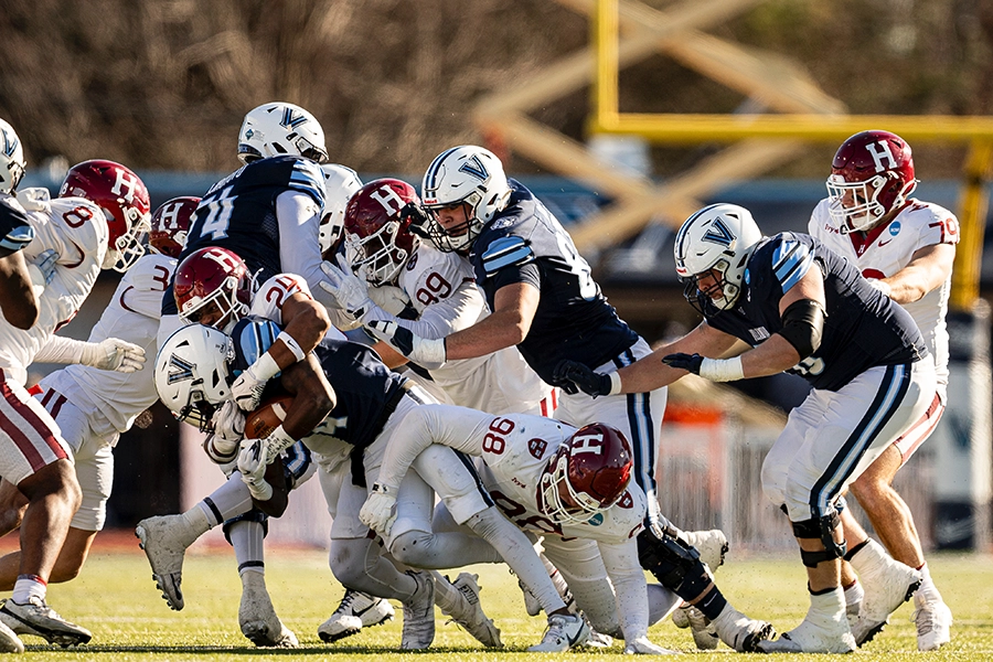 Harvard defenders tackle Villanova ball carrier during a crowded play at the line of scrimmage.