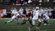 Harvard football player runs with ball as Howard players try to stop him