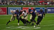 Holy Cross player has ball and Harvard players try to tackle with additional Holy Cross players in pursuit