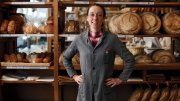 Apollonia Poilâne standing in front of rows of fresh-baked loaves at her family's flagship bakery