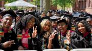 group of Harvard graduates in cap and gown celebrate