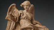 A clay sculpture of a robed angel. 