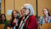 Diane Eck with microphone addressing group