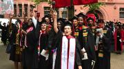Law School graduates in black caps and gowns cheer 