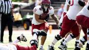 Harvard player 11 runs with the ball with other Harvard players fending off Brown players
