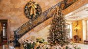 Marble House foyer decorated with a Christmas tree, poinsettias, and a large wreath on the staircase.