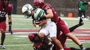 Harvard linebacker tackles Stetson player while a teammate assists during a football game.