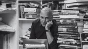 Edwin Frank sits with stacks of books in the background