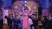 Theatrical performance of H.M.S. Pinafore with actors in sailor costumes and a pink dress.