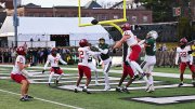 Harvard football players in red jerseys defending against Dartmouth's Hail Mary pass, ensuring victory.