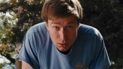 Jacob Roberts in the film Half, wearing a blue T-shirt outdoors, looking directly at the camera.