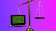 Laptop with green code on screen outweighing an empty brass scale pan on a balance scale against pink-purple background.