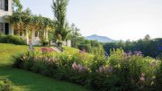 Garden view of Aspet, with vibrant flower beds and Mount Ascutney in the background.