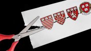 scissors cutting a paper with Harvard shields on a dotted line 