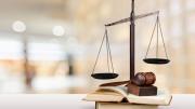 Scales of justice and a gavel resting on open law books with a blurred courtroom background.