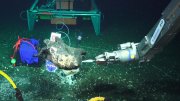 A robotic arm interacting with an underwater object on the ocean floor.