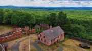 Nineteenth-century prison ruins with brick guardhouse surrounded by forest.