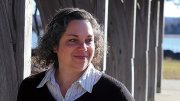 Catherine Zipf smiling, wearing striped shirt and dark sweater outdoors.