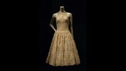 A vintage golden dress with a fitted bodice and flared skirt displayed on a mannequin.
