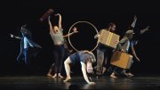 A dynamic dance performance featuring multiple performers engaging with props on stage.