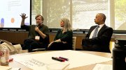 Ned Hall, Rachel Viscomi, and Anthony Foxx speak at a conference table, with a large screen in the background.