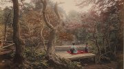 Two women in traditional Japanese clothing sitting on a wooden platform near a tranquil pond, surrounded by autumn foliage.