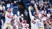 Football players in white and maroon uniforms celebrating a play on the field.